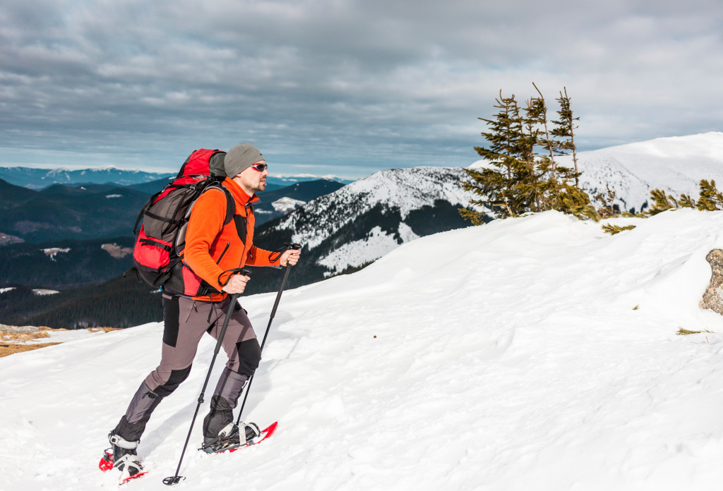 A man climbing snow mountain with snowshoes on top of mountain 